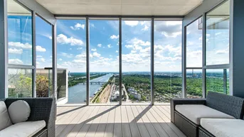 Geräumiger Wohnbereich mit raumhohen Fenstern und weitem Blick über die Stadt und den Fluss.