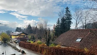 Blick auf die umliegende Landschaft mit Häusern, Bäumen und einem bewölkten Himmel.