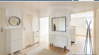 Heller Flur mit Parkettboden, Spiegel, Garderobe und weißem Schuhschrank.