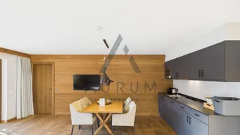 Moderne Küche mit dunklen Schränken, Holzwandverkleidung und Essbereich.