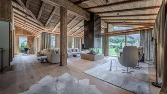 Geräumiges Wohnzimmer im alpinen Stil mit Holzbalkendecke, modernem Kamin und Bergblick.