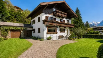 Traditionelles Haus im alpinen Stil mit großem Garten, gepflasterter Auffahrt und Bergblick.