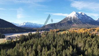 Panoramablick auf die majestätische Berglandschaft mit dichten Wäldern und einem malerischen Dorf.