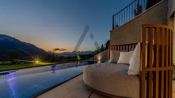 Exklusiver Infinity-Poolbereich mit Liegemöbeln und atemberaubendem Bergblick bei Sonnenuntergang.