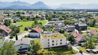 Luftaufnahme eines modernen Wohngebäudes mit Gründach in einer ländlichen Umgebung mit Bergblick.