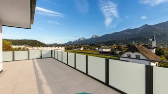 Geräumige Dachterrasse mit Fliesenboden und weitem Blick auf die umliegende Berglandschaft und das Dorf.