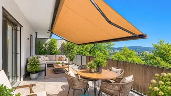 Geräumige Terrasse mit bequemen Loungemöbeln, Esstisch und ausfahrbarer Markise, umgeben von viel Grün.