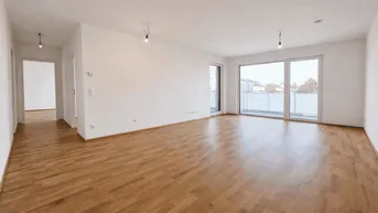 Heller, leerer Wohnbereich mit Parkettboden und Zugang zu einem Balkon.