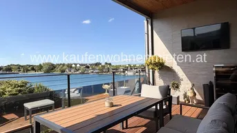 Sonnige Terrasse mit Esstisch, bequemer Sitzgruppe und weitem Blick auf den See.