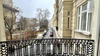 Blick vom Balkon auf die belebte Straße und die umliegenden historischen Gebäude.