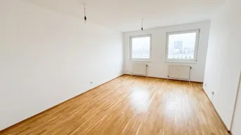 Helles Zimmer mit Parkettboden, weißen Wänden und Blick auf die Stadt.