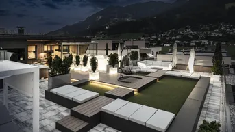 Geräumige Dachterrasse mit modernen Lounge-Möbeln, Beleuchtung und Bergblick bei Nacht.