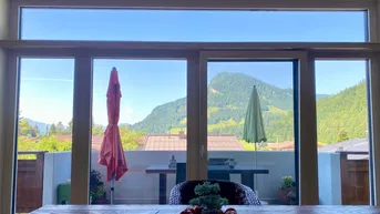 Panoramablick auf die Berge und die umliegende Landschaft durch große Fenster vom Essbereich.