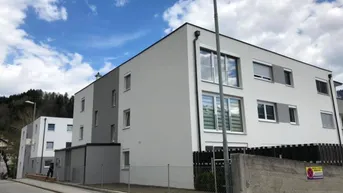 Moderne Mehrfamilienhäuser mit weißer und grauer Fassade unter blauem Himmel.