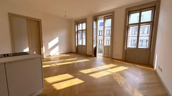 Heller offener Wohnbereich mit Fischgrätparkett, hohen Fenstern und viel natürlichem Licht.