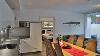 Moderne offene Küche mit Essbereich und Blick in ein Schlafzimmer, hell und funktional eingerichtet.