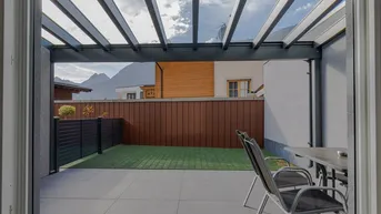 Blick von der Terrasse auf den privaten Gartenbereich und die umliegende Berglandschaft.
