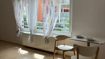 Gemütlicher Essbereich am Fenster mit hellem Holzboden und Blick ins Grüne.
