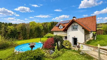 Charmantes Einfamilienhaus mit Garten, Aufstellpool und Photovoltaikanlage unter blauem Himmel.