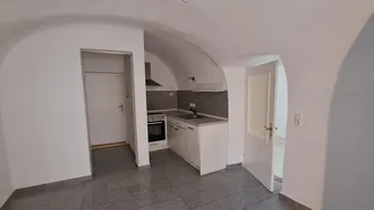 Kleine Küche mit Gewölbedecke und Fliesenboden, ausgestattet mit Herd und Spüle.