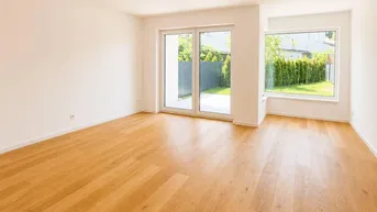 Heller, leerer Raum mit Holzboden, großen Fenstern und Zugang zu einer kleinen Terrasse.