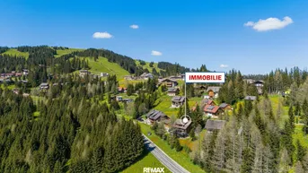 Luftaufnahme eines Chalets in einer malerischen Berglandschaft mit umliegenden Wäldern und Wiesen.