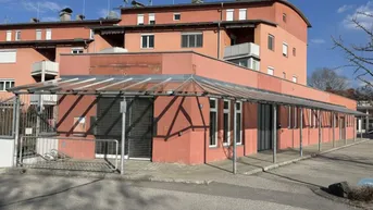 Gebäude mit rötlicher Fassade und einer langen Glasüberdachung über dem Eingangsbereich.