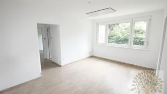 Helles Zimmer mit Laminatboden und großen Fenstern, die einen Blick ins Grüne bieten.