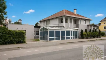 Außenansicht des Hauses mit einem großen, modernen Wintergarten und gepflegten Pflanzen.