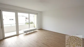 Helles Wohnzimmer mit Parkettboden und Zugang zu einem Balkon, ideal für entspannte Stunden.