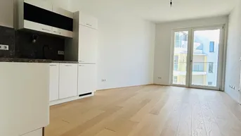 Heller offener Wohnbereich mit integrierter Küchenzeile und Holzboden.