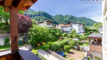Geräumiger Balkon mit Holzboden und schöner Aussicht auf den Garten und die umliegenden Berge.