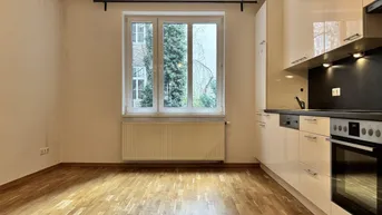 Moderne Küche mit weißen Hochglanzfronten, integrierten Geräten und Blick ins Grüne.