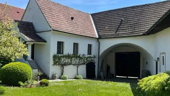 Historisches Gebäude mit gepflegtem Rasen und begrüntem Innenhof unter blauem Himmel.