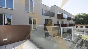 Geräumiger Balkon mit Glasgeländer und Blick auf die moderne Wohnanlage.