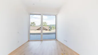 Heller Raum mit Holzboden und großen Fenstern, die viel Tageslicht hereinlassen und eine weite Aussicht bieten.