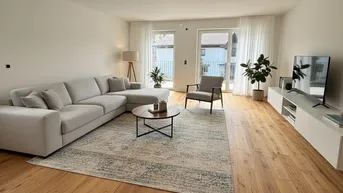 Helles Wohnzimmer mit modernem Sofa, Holzboden und Zugang zu einem Außenbereich.