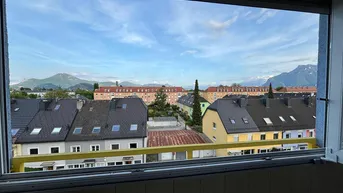 Panoramablick vom Balkon über die Dächer der Stadt mit majestätischen Bergen im Hintergrund.