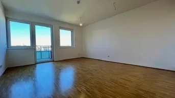 Helles, leeres Zimmer mit Parkettboden und Zugang zu einem Balkon, ideal für ein Wohnzimmer.