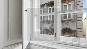 Fenster mit Blick auf eine historische Gebäudefassade mit Stuckverzierungen und klassischen Details.