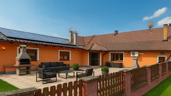 Große Außenterrasse mit Sitzgelegenheiten und Grillplatz, umgeben von einem gepflegten Garten.