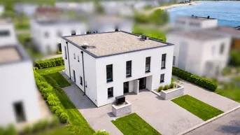 Moderne Doppelhaushälfte mit Flachdach und gepflegtem Vorgarten in Wassernähe.