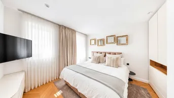 Gemütliches Schlafzimmer mit Doppelbett, Fischgrätparkett und viel Tageslicht durch große Fenster.