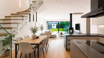 Moderner offener Wohn-Essbereich mit Holzboden, eleganter Treppe und Blick in den Garten.