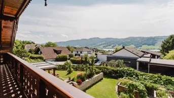 Weitläufiger Ausblick vom Balkon über die grüne Landschaft und einen See in der Ferne.