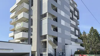 Modernes Mehrfamilienhaus mit mehreren Balkonen und einer Tiefgaragenzufahrt.
