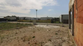 Baustelle mit unbebautem Grundstück und Blick auf die Umgebung unter bewölktem Himmel.
