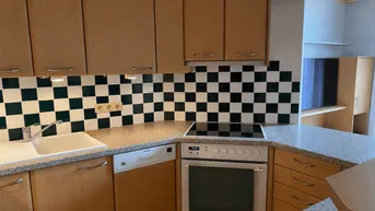 Funktionale Küche mit Holzschränken, Granit-Arbeitsplatte und schwarz-weiß gefliestem Spritzschutz.