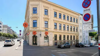 Elegantes Eckgebäude in der Stadt mit klassischer Architektur und großen Fenstern an einer belebten Straße.