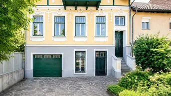 Historische Fassade mit gelbem Anstrich, grünen Fensterläden und integrierter Garage.